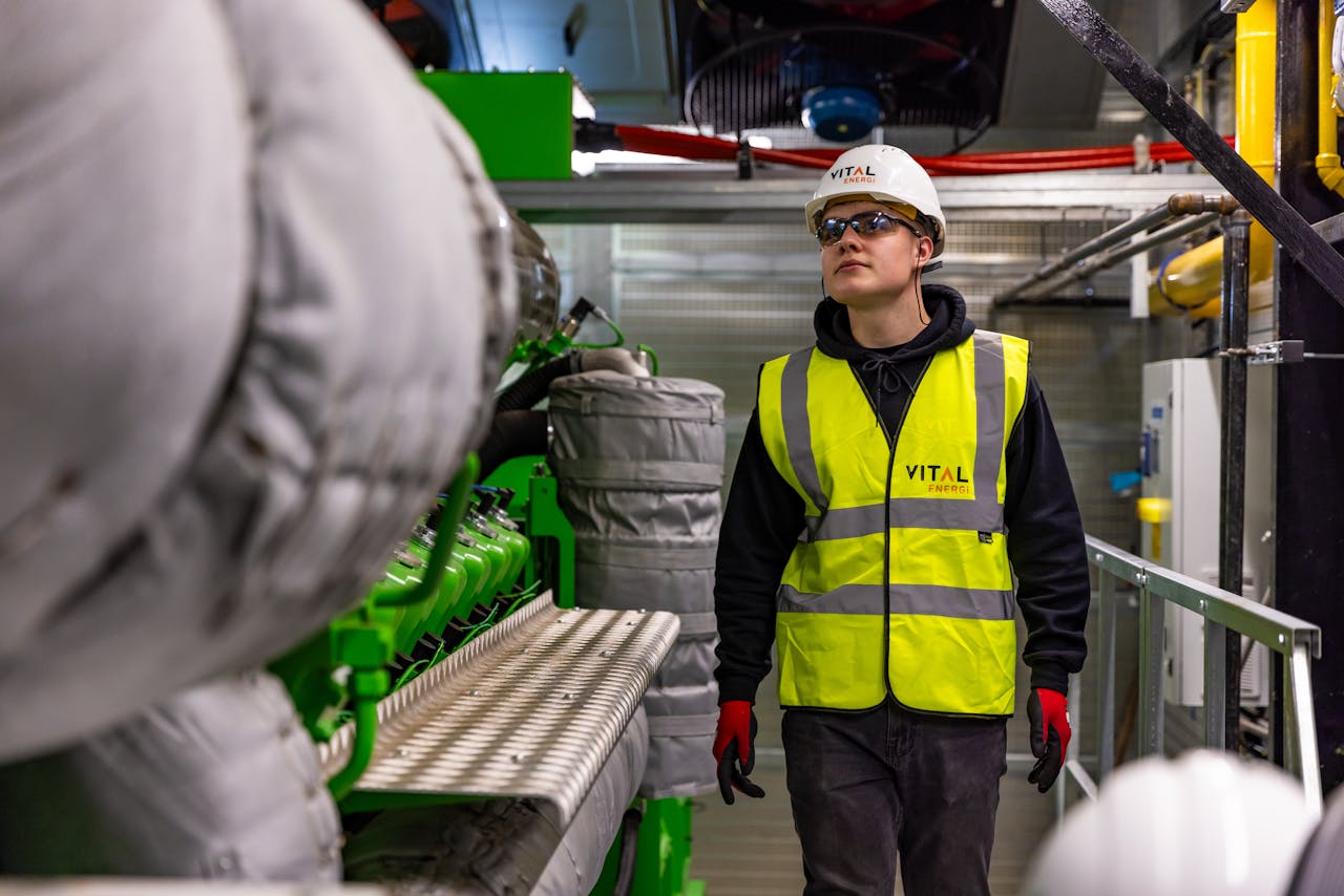 Man in safety gear inspecting factory equipment, ensuring quality control and safety standards.